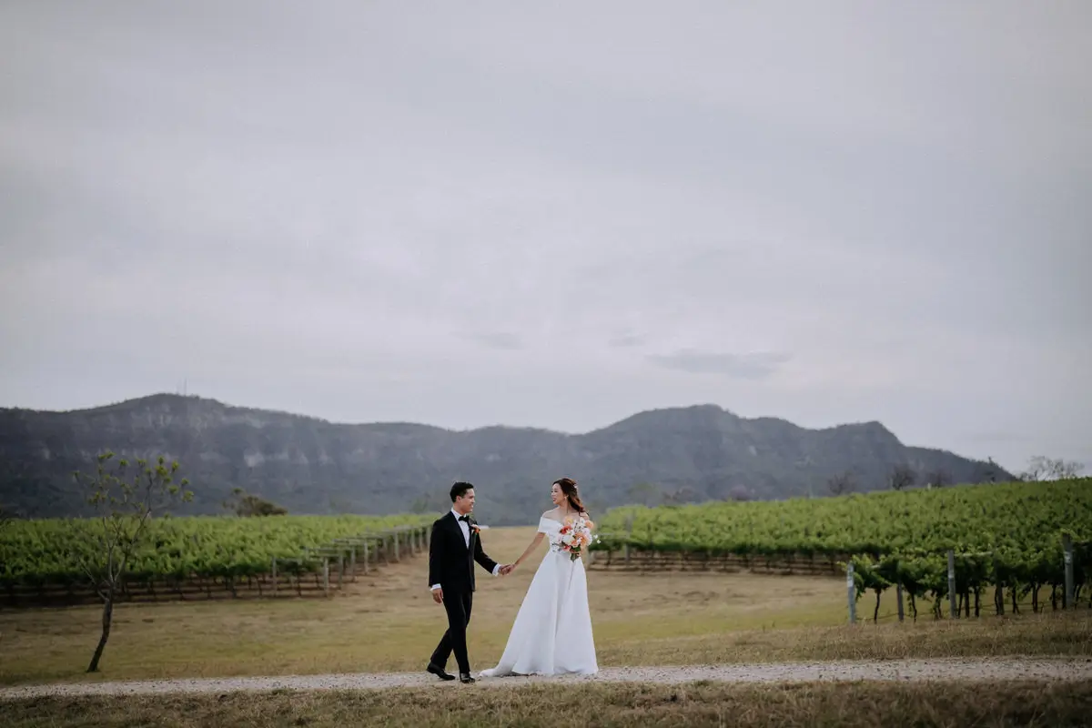 Bride and groom walking along the vineyards at Enzo Hunter Valley wedding venue